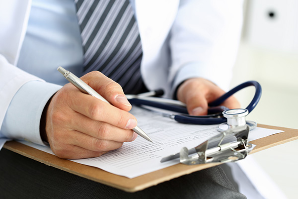 A doctor writing on a clipboard